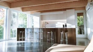 Een moderne keuken met een centraal eiland, barkrukken en grote ramen.