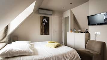Een hotelkamer met een bed, een bank, een aan de muur bevestigde televisie en een airconditioning.