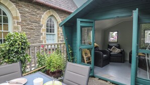 A stone building with a teal door and a small patio area with a table and chairs. - Upper Vestry (Llandysul)