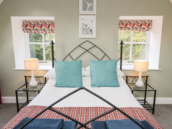 A neatly made bed with a patterned bedspread, two matching pillows, and two bedside lamps.