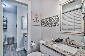 A modern bathroom with a granite countertop, a large mirror, and a decorative anchor wall piece. - Playa Bonita 30A Seagrove Beach, 100 Steps to snow white sand! (Santa Rosa Beach)