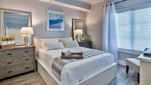 Um quarto moderno com cama, mesas de cabeceira, escrivaninha e janela com persianas.