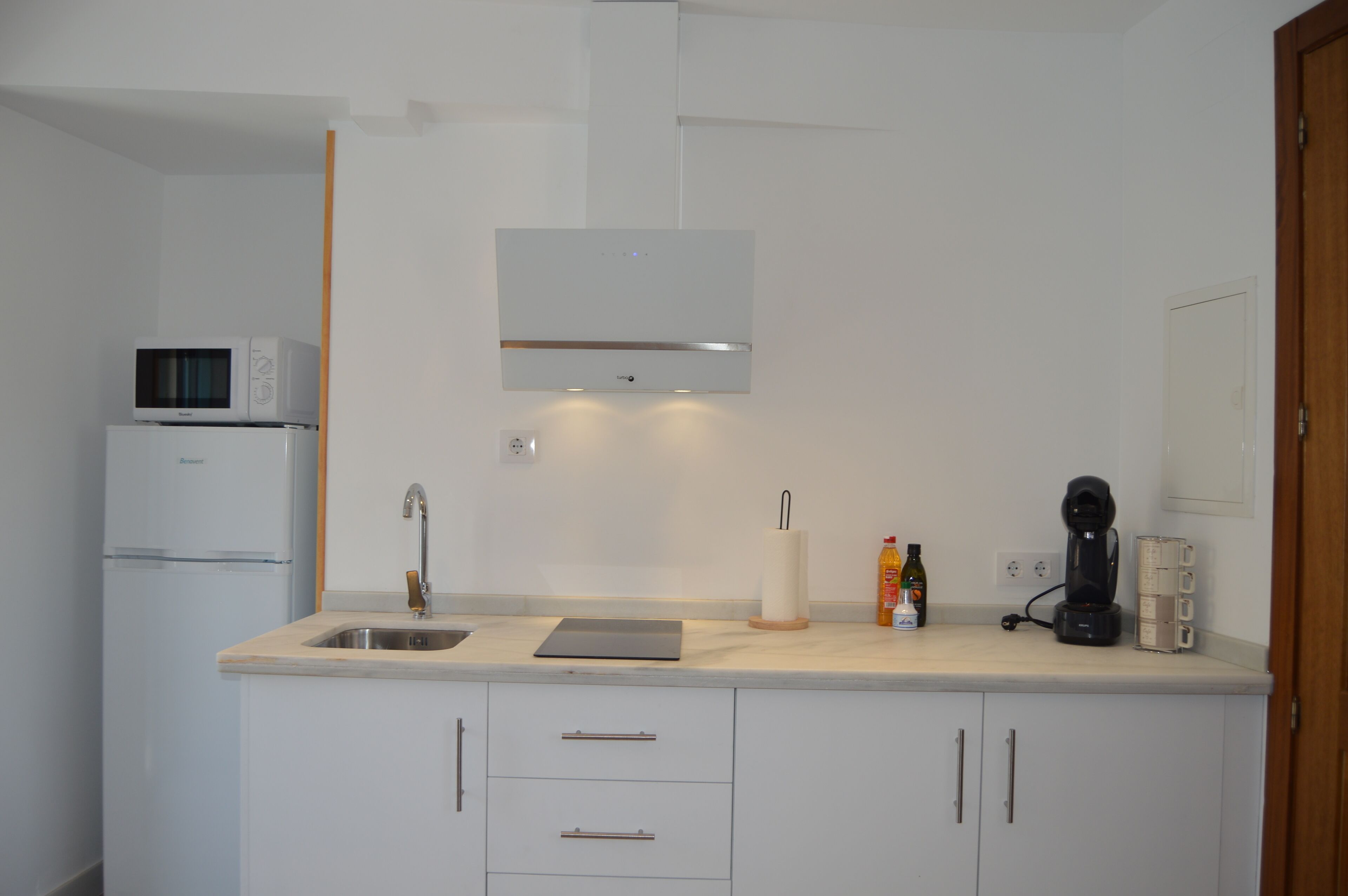 A modern kitchen with a built-in microwave, a coffee maker, and a sink.