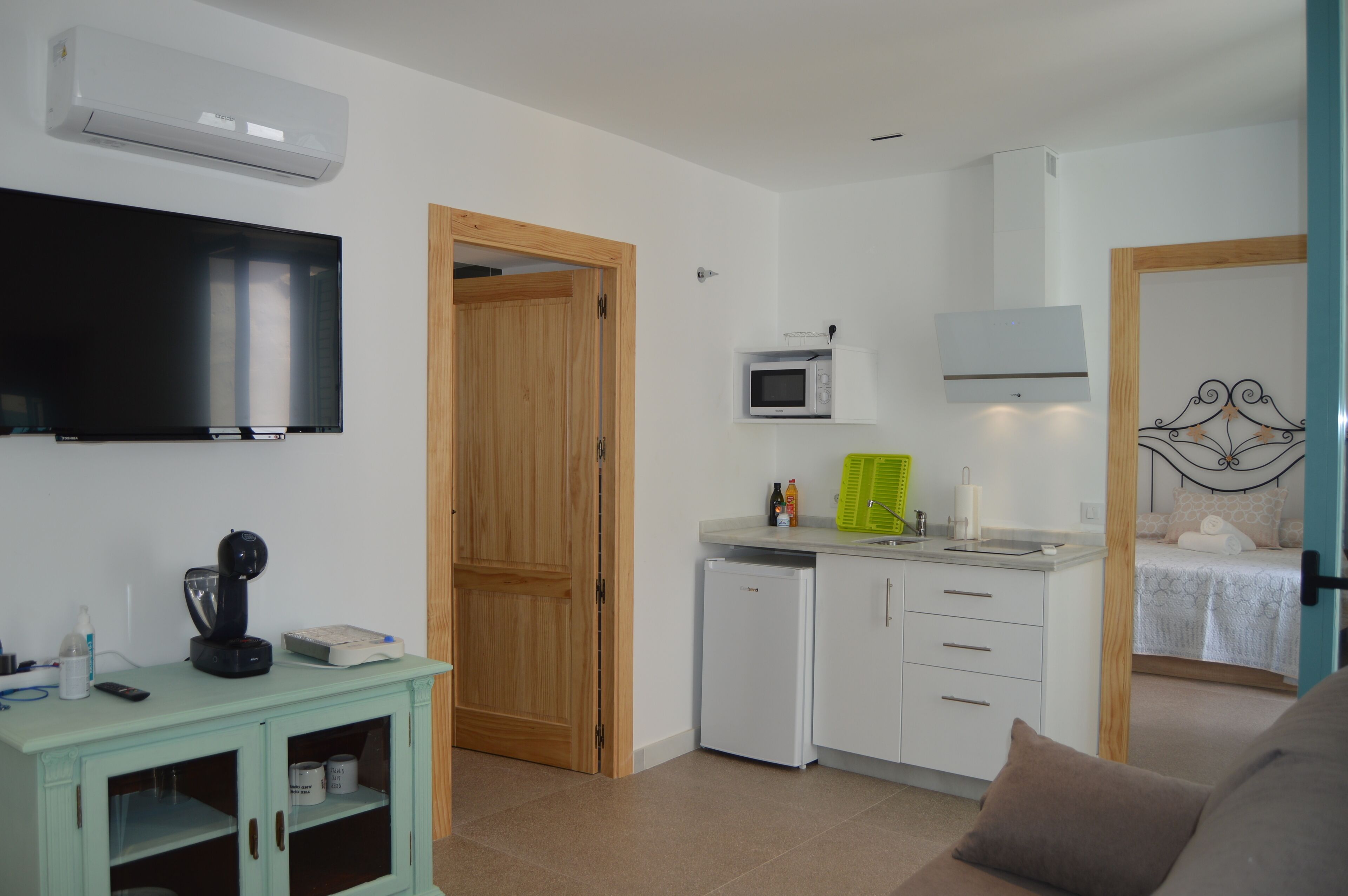 Un espacio habitable compacto con kitchenette, televisor, microondas y cama.