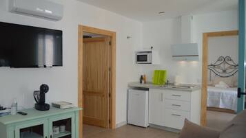 Un espacio habitable compacto con kitchenette, televisor, microondas y cama.
