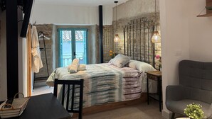 A bedroom with a bed, bedside table, chair, and a view of the outside. - El Aljibe Relax (Córdoba)