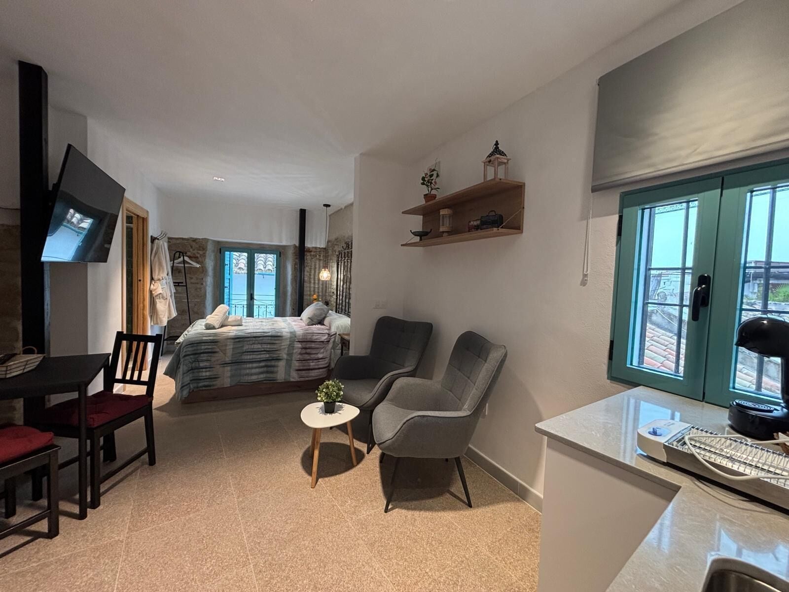 Ett modernt hotellrum med en säng, en sittgrupp, en TV och utsikt genom fönstret.