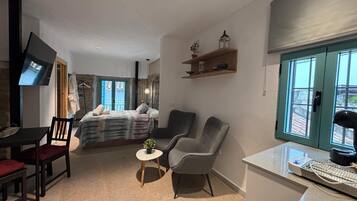 Ett modernt hotellrum med en säng, en sittgrupp, en TV och utsikt genom fönstret.