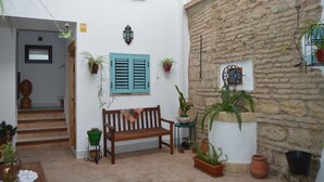 A courtyard with a wooden bench, potted plants, a stone wall, and a sign reading "EL ALJIBE". - El Aljibe Relax (Córdoba)