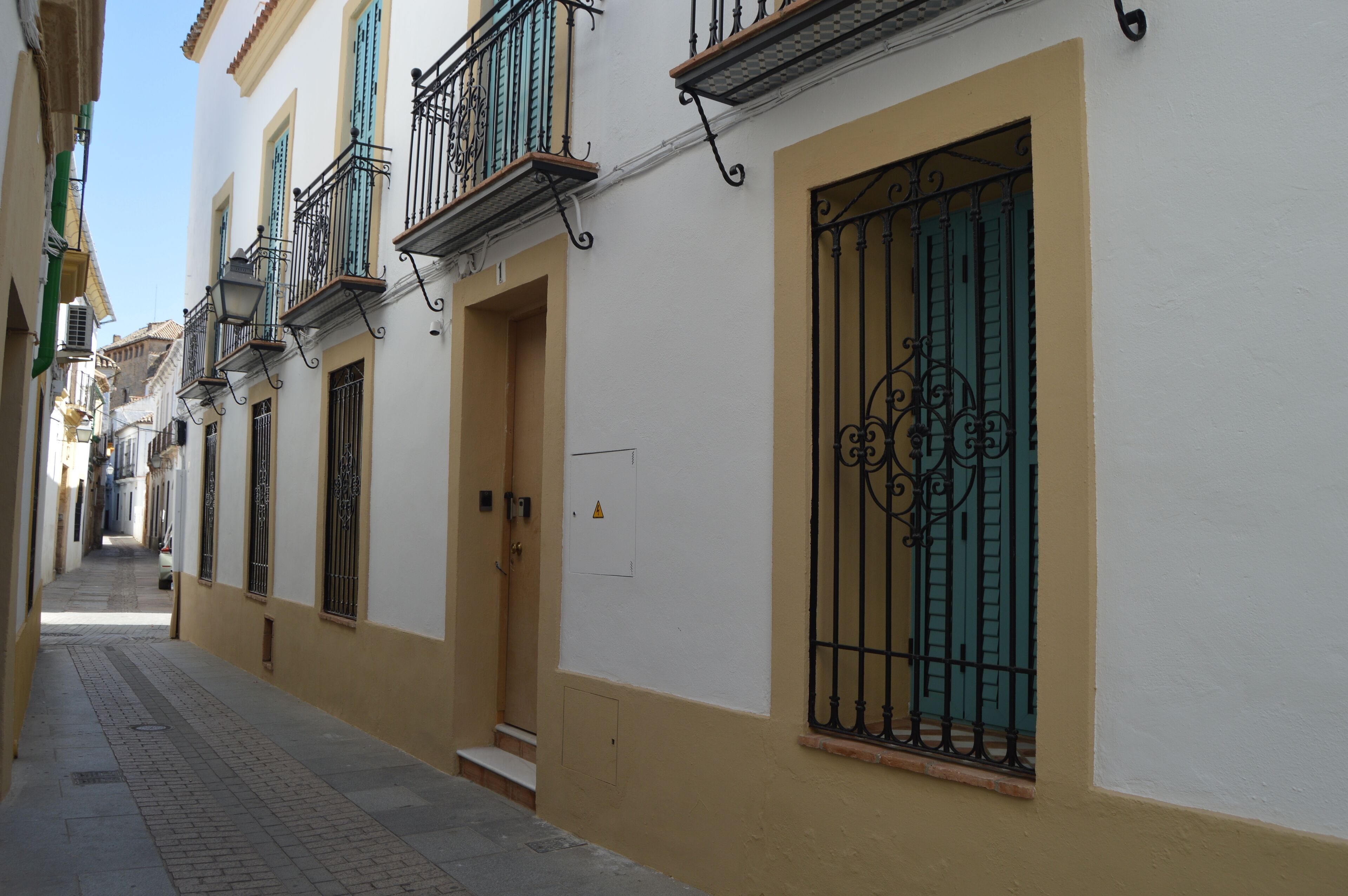 A narrow street with buildings featuring balconies and barred windows.