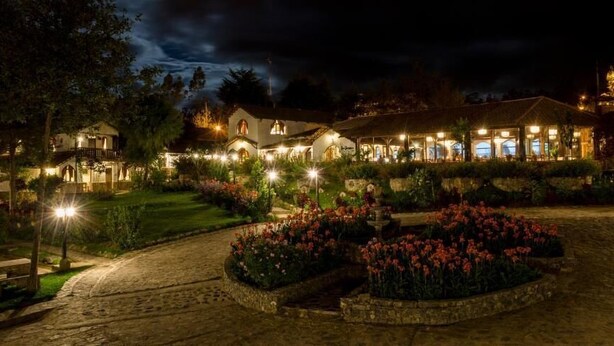 A well-lit hotel with multiple buildings, a garden with flowers, and a pool area. - Hotel Villa de Paris (Chachapoyas)