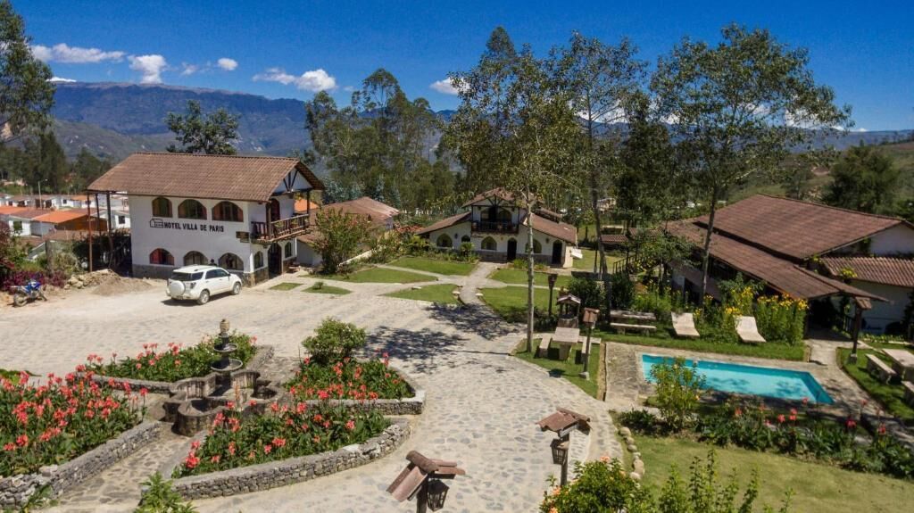 Un hotel con piscina, jardín y vistas a la montaña.