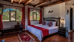 A bedroom with a wooden ceiling, a bed with a red and white bedspread, two bedside tables, and a nightstand with a lamp. - Hotel Villa de Paris (Chachapoyas)