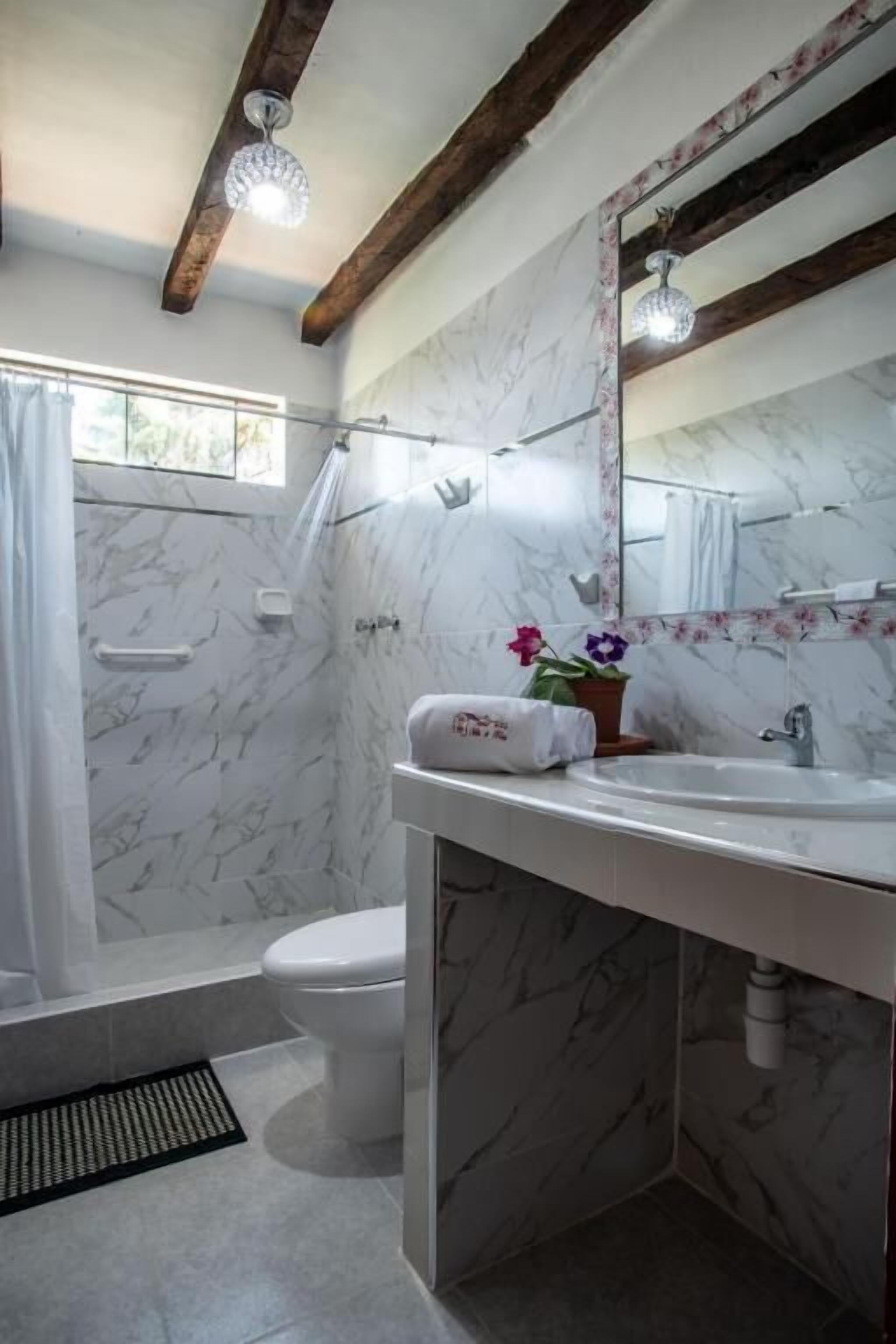 A bathroom with a marble floor, a white sink, a toilet, and a shower area.