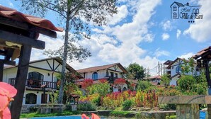 A hotel with multiple-story buildings, a swimming pool, and a garden with colorful flowers. - Hotel Villa de Paris (Chachapoyas)