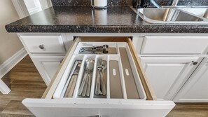 A kitchen with a drawer containing silverware.