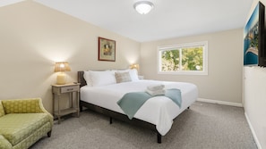 A bedroom with a bed, bedside lamps, a window, and a painting on the wall.