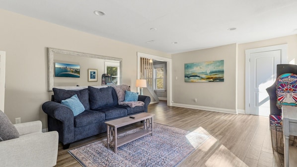 A living room with a sofa, coffee table, and artwork on the walls.