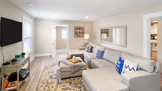 A living room with a grey sofa, a coffee table, and a TV. There is a patterned rug on the floor. - Newly UPD home in DT Libertyville Near Naval Base! (Libertyville)