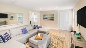 A modern living room with a grey sofa, a coffee table, and a painting on the wall. - Newly UPD home in DT Libertyville Near Naval Base! (Libertyville)