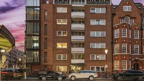 A multi-story building with a mix of modern and traditional architecture, featuring balconies and large windows. - Elegant 2BD Knightsbridge Retreat Steps from Harrods (London)