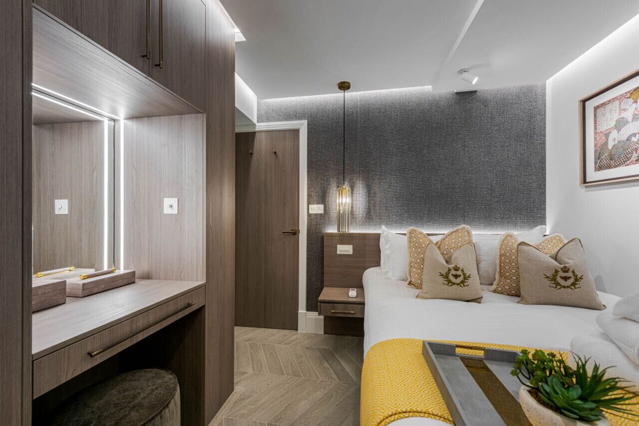 A modern bedroom with a bed, bedside table, and a desk with a mirror.