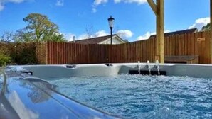 Een hottub met een houten terras en een houten omheining op de achtergrond.