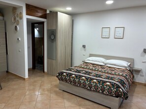 A bedroom with a bed, a wooden wardrobe, a mirror, and two motivational wall art pieces.