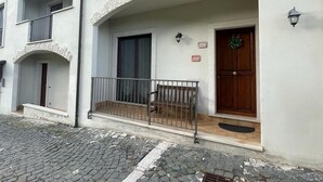 Ein Gebäude mit einer Stein-Fassade, einer Holztür, einer Bank davor und einem Schild darüber.