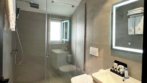 Un baño moderno con cabina de ducha de vidrio, inodoro y tocador con espejo.