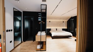 Una habitación de hotel moderna con una cama grande, un vestidor y un espejo.