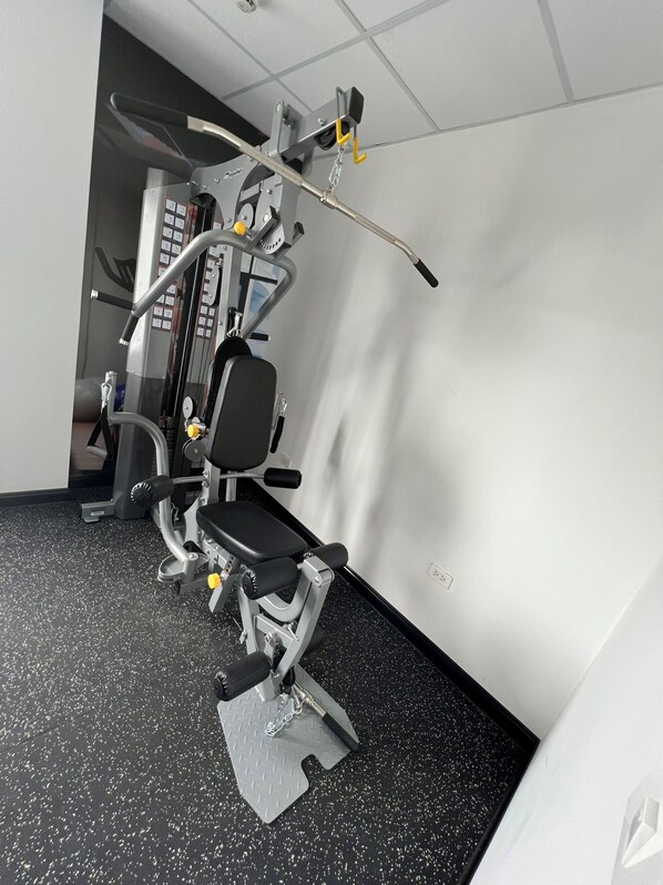 A gym with exercise equipment, a bench, and a wall-mounted control panel.