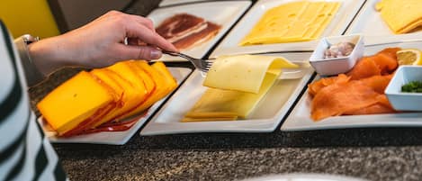 Un bufé con diversas opciones de comida, incluyendo queso, jamón y salmón ahumado.