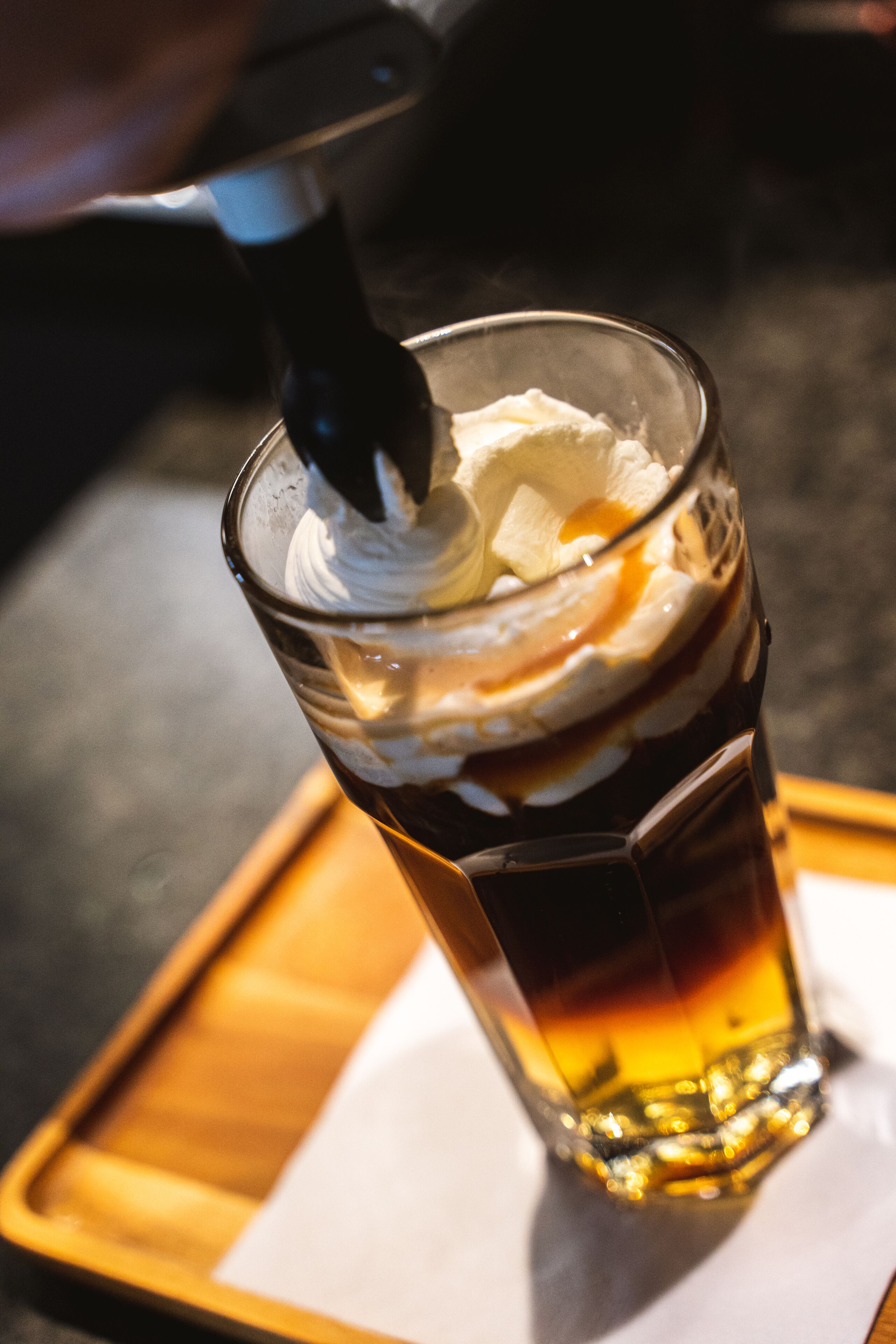 Ett glas med en drink i flera lager, troligen en cocktail, står på ett bricka.