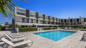 Ett modernt hotell med en stor pool, flera balkonger och solstolar.