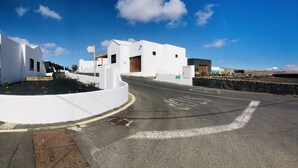 A white building with a curved driveway and a stone wall. - Casita Bellavista with great views in Mozaga (Mozaga)