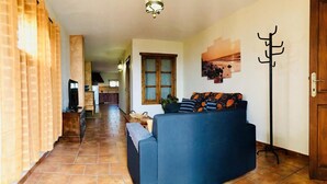 A living room with a sofa, a television, and a kitchen in the background. - Casita Bellavista with great views in Mozaga (Mozaga)