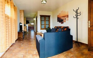 Ein Wohnzimmer mit einer Couch, einem Fernseher und einer Küche im Hintergrund.