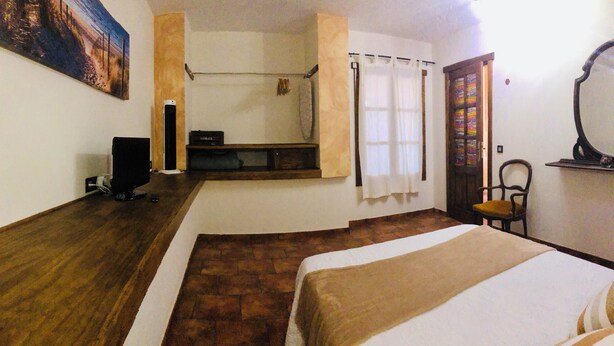 A hotel room with a bed, a chair, a desk with a computer, a painting on the wall, and a window with curtains. - Casita Bellavista with great views in Mozaga (Mozaga)