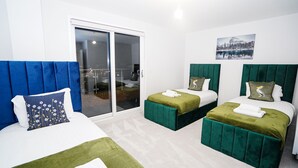 A hotel room with two beds, a sliding glass door to a balcony, and a painting of a snowy landscape. - Penthouses in Slough (Slough)