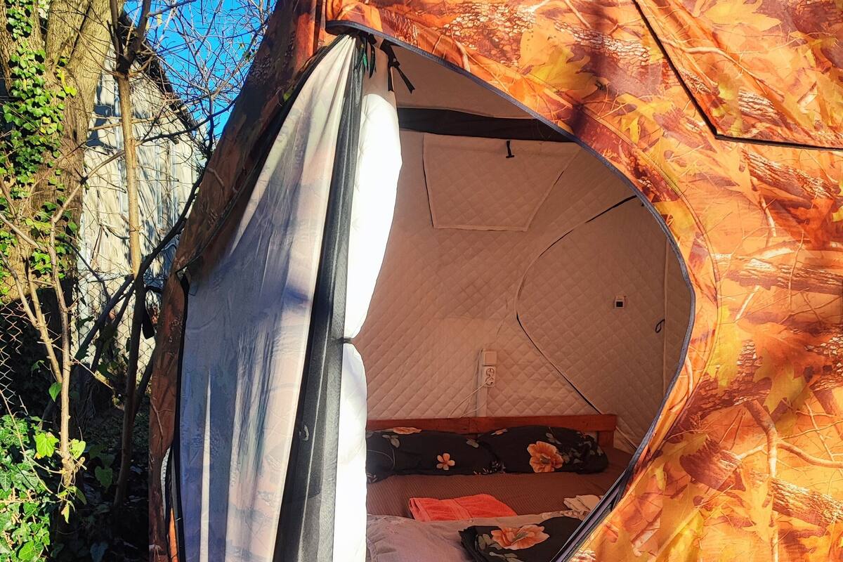 Une tente dont l’entrée est entrouverte, laissant apercevoir un lit à l’intérieur.