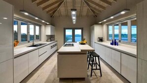 Cozinha moderna com ilha central, grandes janelas e vista para o exterior.