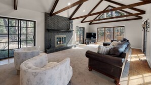Un salón espacioso con chimenea, ventanas amplias y un techo alto con vigas a la vista.