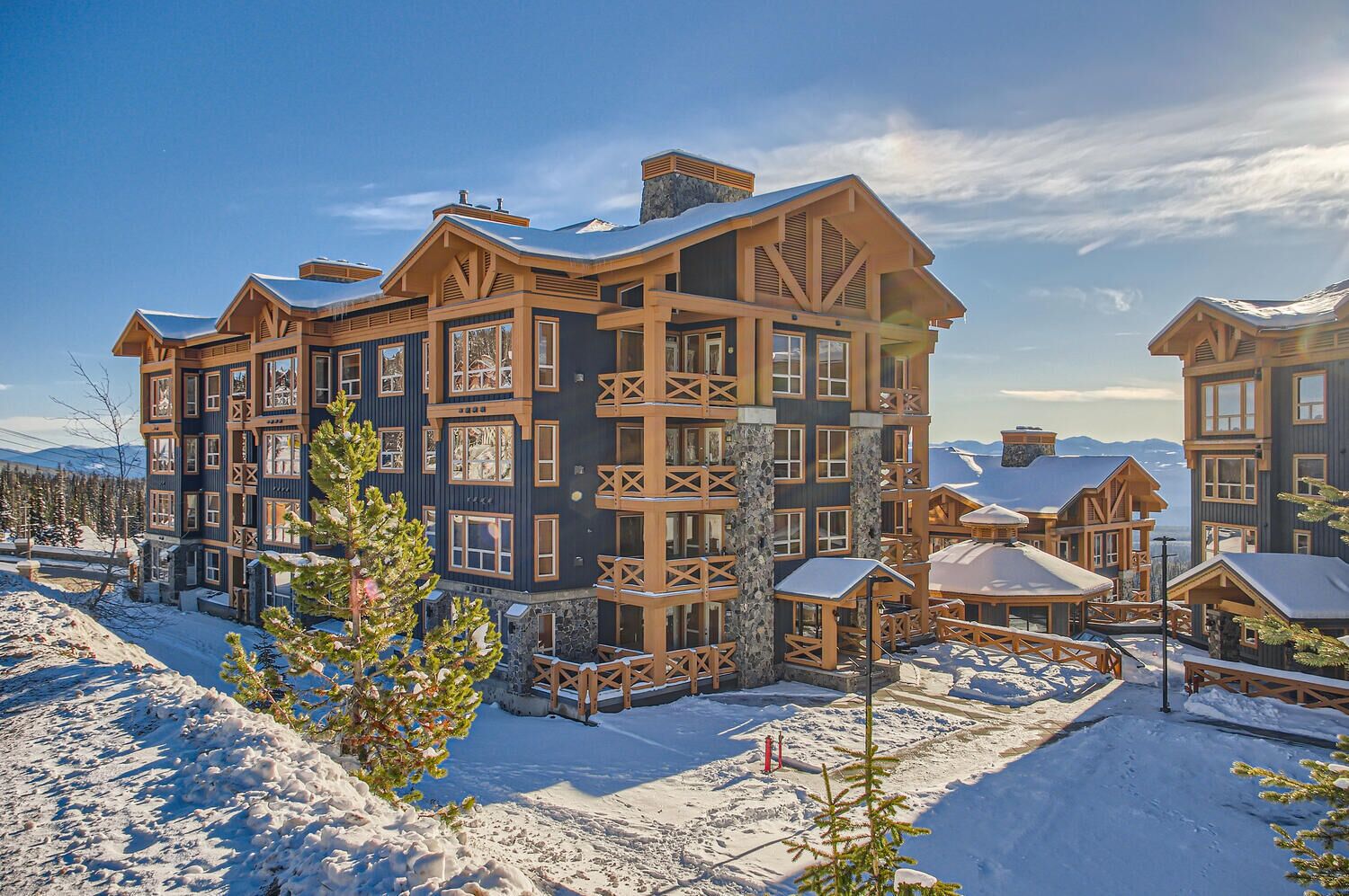 A multi-story lodge with a symmetrical facade, large windows, and a snow-covered landscape.