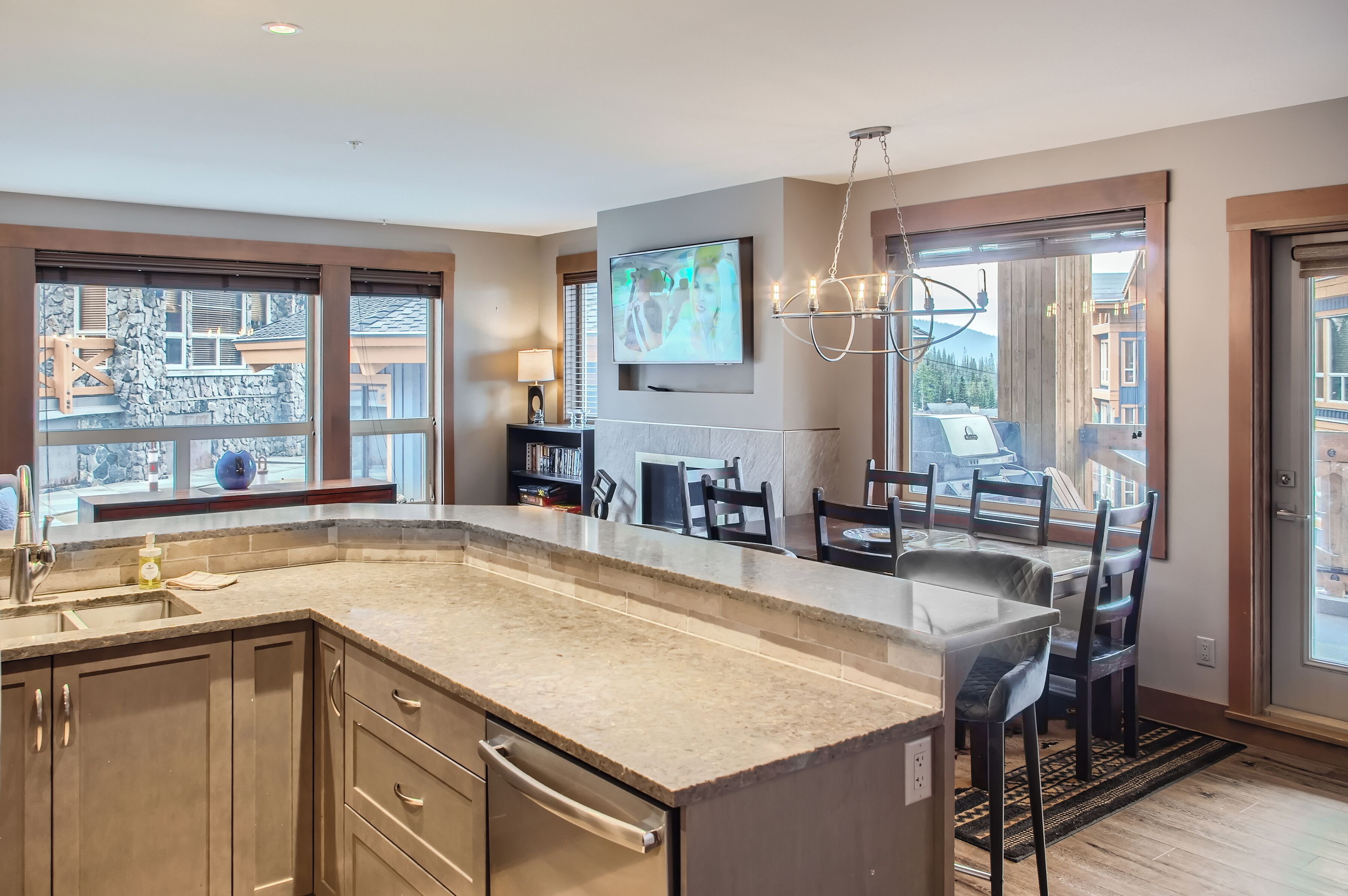 Cocina moderna con una isla grande, armarios empotrados y un comedor con candelabro.