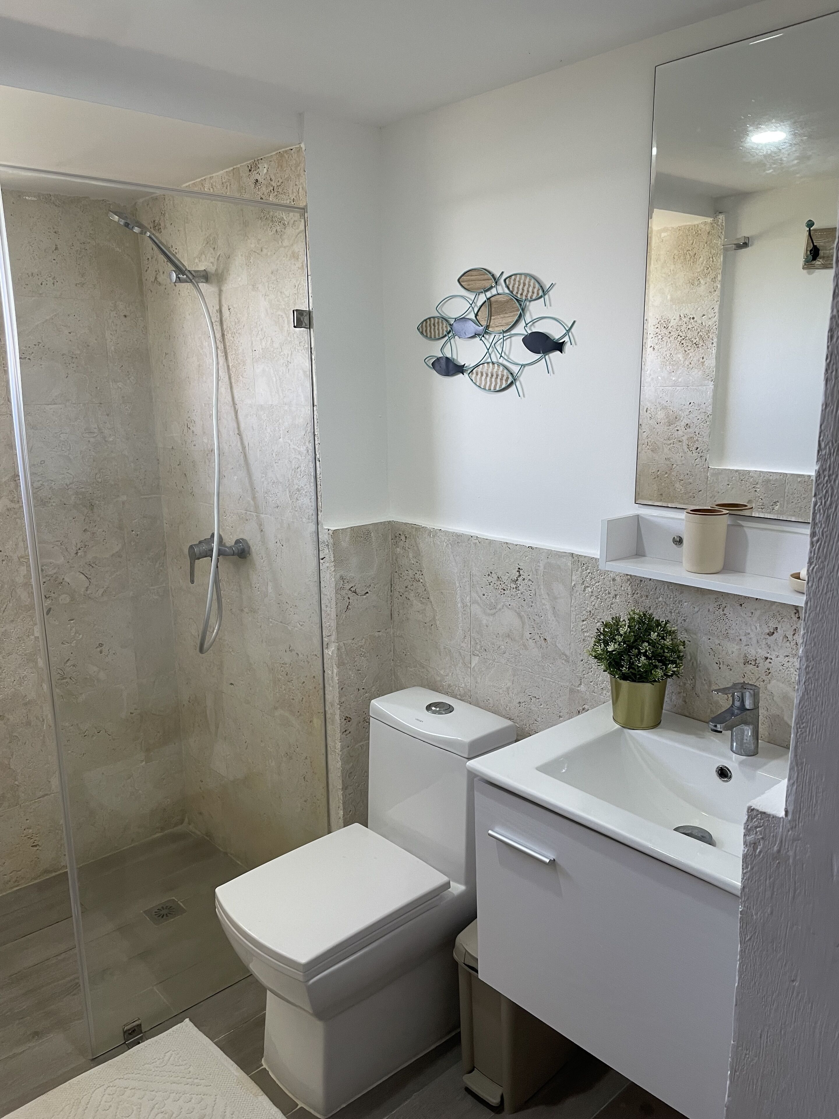 Ein Badezimmer mit Dusche, Toilette, Waschbecken und einem dekorativen Wandbild.