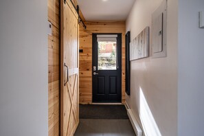 A narrow hallway with wooden walls, a black door, and a small window. - Tremblant Prestige - Les Eaux 233-2 (Mont-Tremblant)