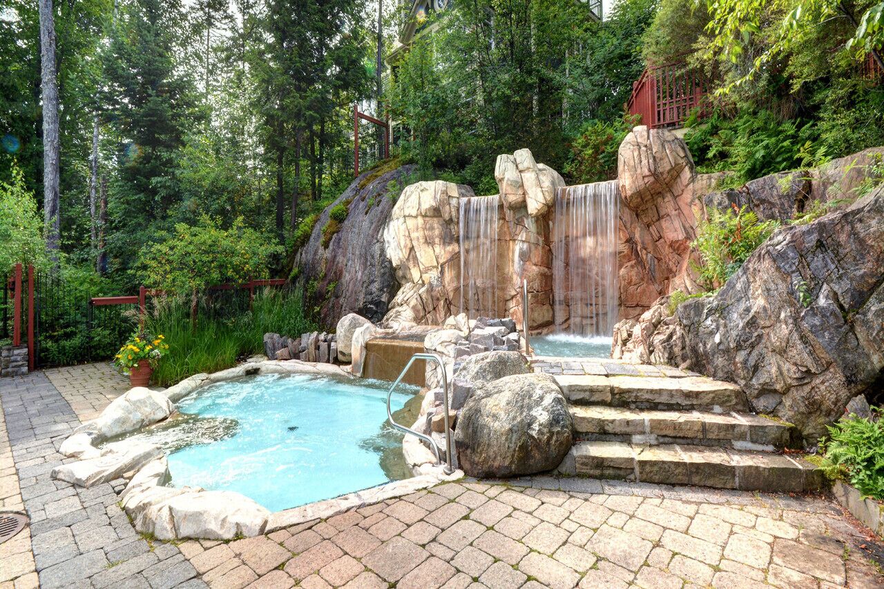 Ein natürliches Quellgebiet mit einem Pool, Steintreppen und einem Wasserfall.