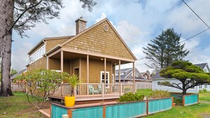 A two-story house with a covered porch, a fenced yard, and a large tree. - Treasure Paradise MCA#522-Only 1 1/2 blocks to the beach. Close to everything (Manzanita)