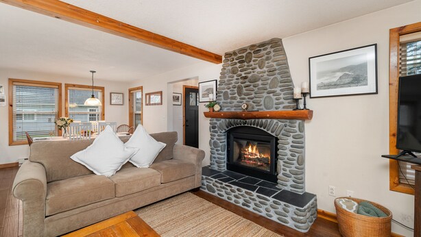 A cozy living room with a stone fireplace, a beige sofa, and a television. - Treasure Paradise MCA#522-Only 1 1/2 blocks to the beach. Close to everything (Manzanita)